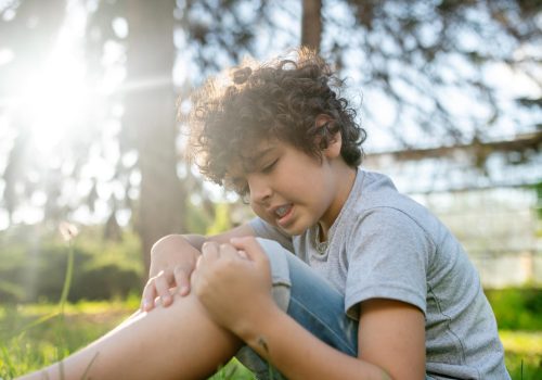 focused-dark-haired-boy-examining-his-damaged-knee