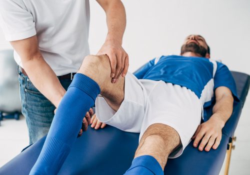 physiotherapist-massaging-leg-of-football-player-i-2023-11-27-05-34-55-utc-web